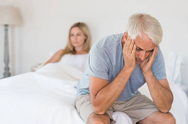 Man sitting on the edge of the bed looking tired and stressed